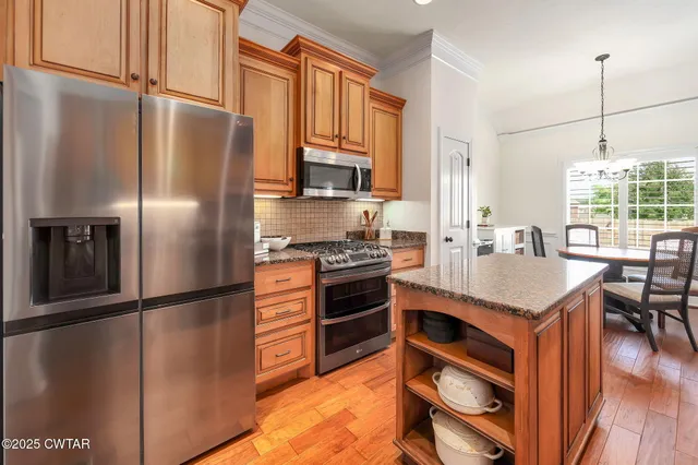 a kitchen with stainless steel appliances granite countertop a refrigerator a stove a sink and a refrigerator