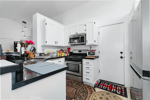 a kitchen with granite countertop a refrigerator stove and sink