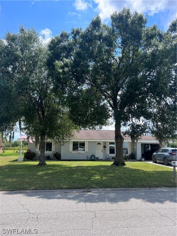 a front view of a house with a yard and large trees