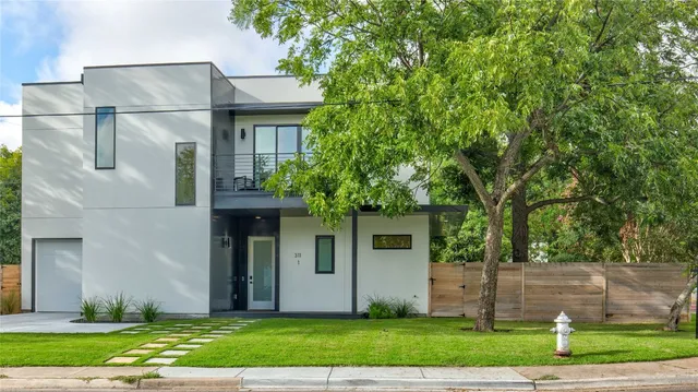 a front view of a house with a yard and a tree