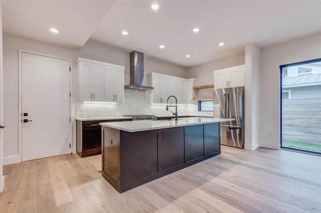 a large kitchen with stainless steel appliances kitchen island granite countertop a refrigerator and a sink