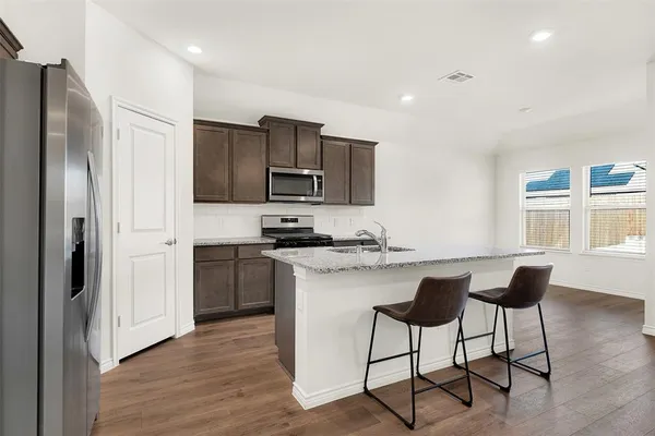 a kitchen with stainless steel appliances a sink a stove a refrigerator cabinets and a dining table