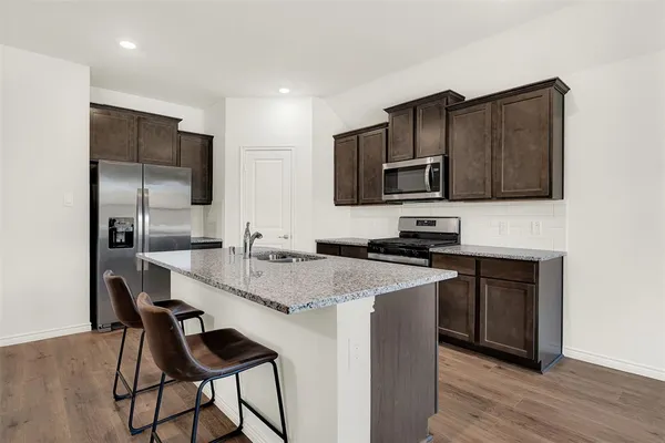 a kitchen with stainless steel appliances kitchen island granite countertop a stove a sink a microwave and a refrigerator