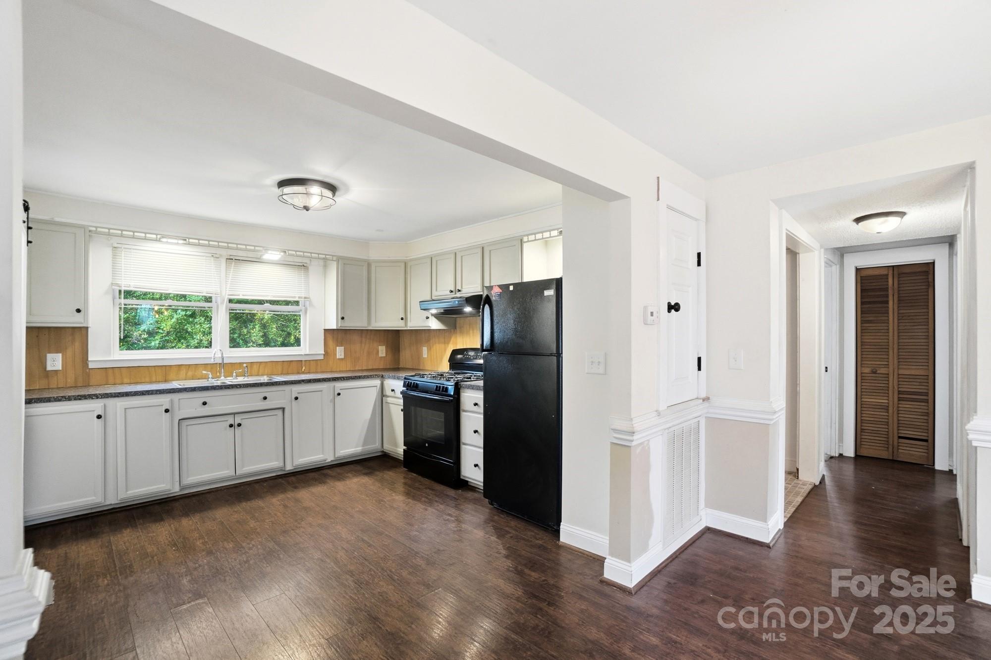 149 Swink Street Southwest Concord, NC 28027 - Photo 12 of 27 a large kitchen with a refrigerator a sink dishwasher a stove and white cabinets with wooden floor