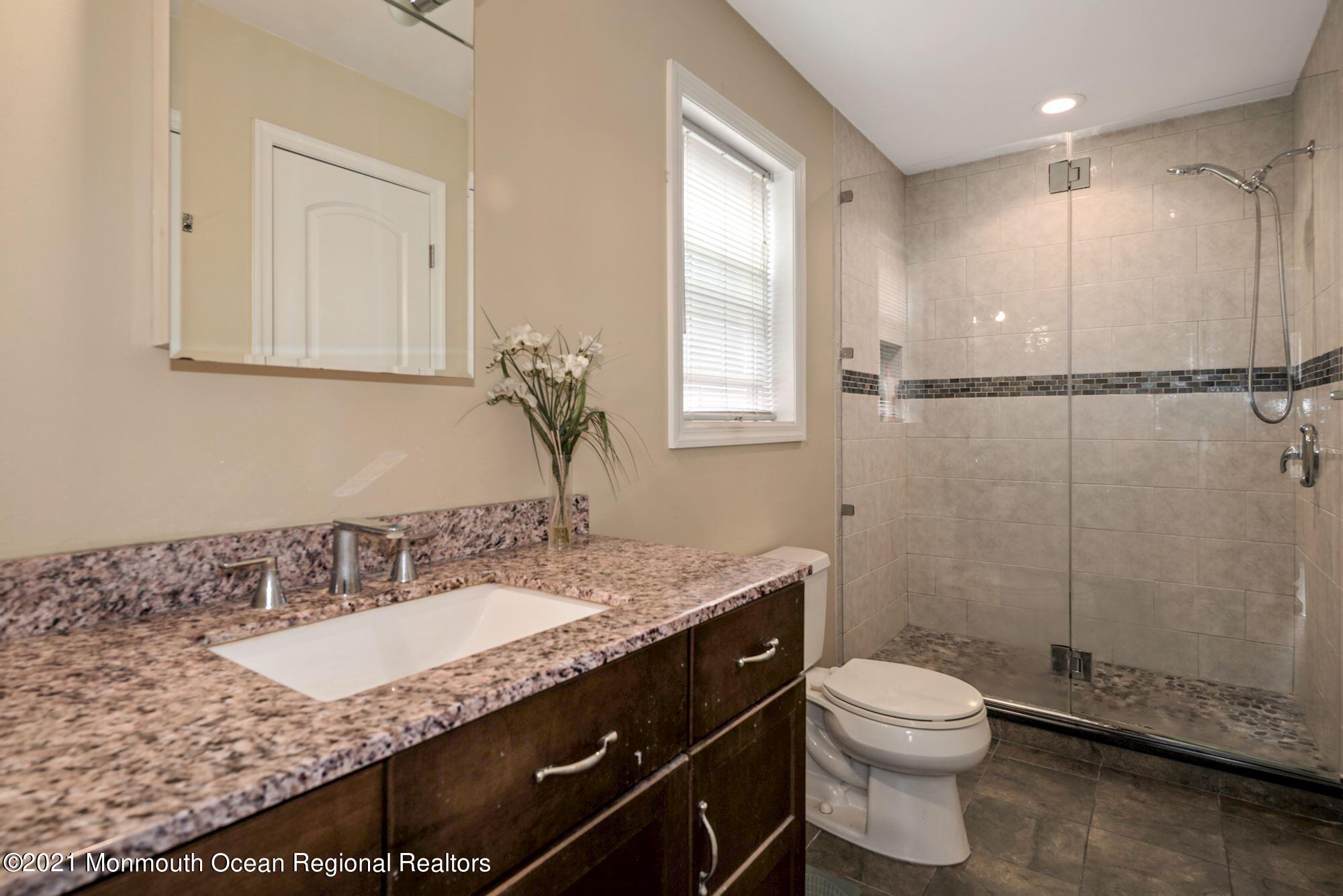 657 Drum Point Road Brick, NJ 08723 - Photo 11 of 25 a bathroom with a granite countertop sink a mirror and a toilet