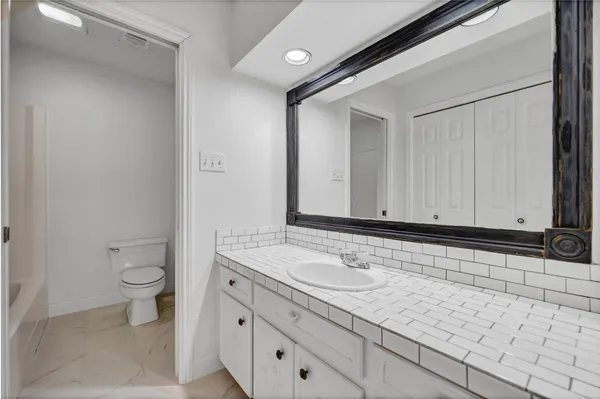 a bathroom with a granite countertop sink and a toilet