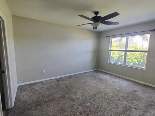 an empty room with windows and ceiling fan