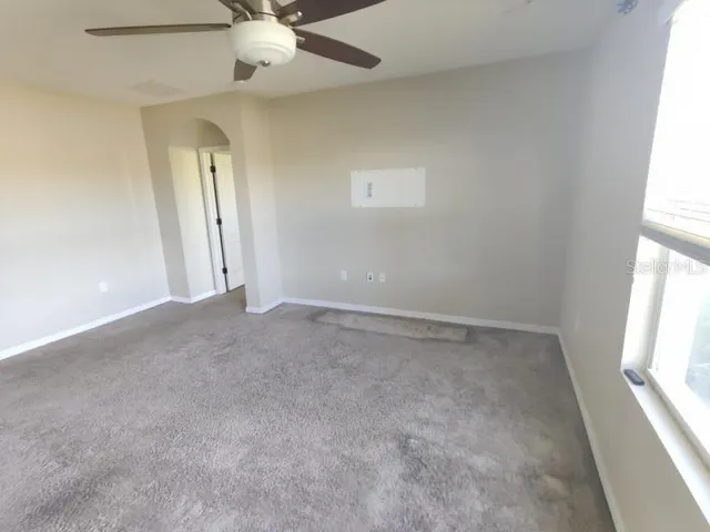 an empty room with a window and a fan