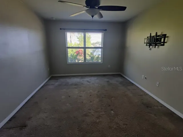 an empty room with windows and chandelier fan