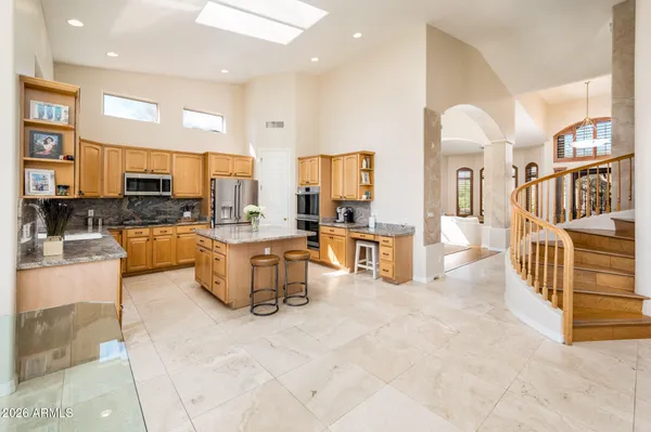 a kitchen with stainless steel appliances granite countertop a refrigerator a stove a sink a dining table and chairs