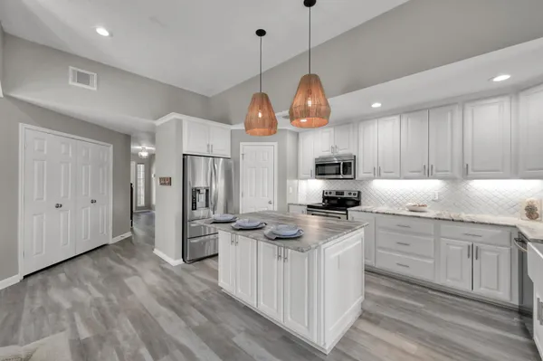 a kitchen with stainless steel appliances granite countertop a sink a stove and a wooden floors