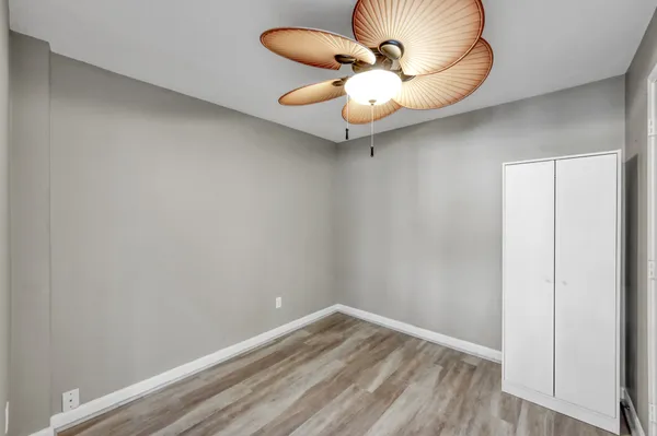 a view of a room with a chandelier fan and wooden floor