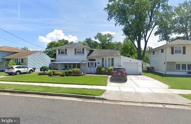 a front view of a house with a garden and trees