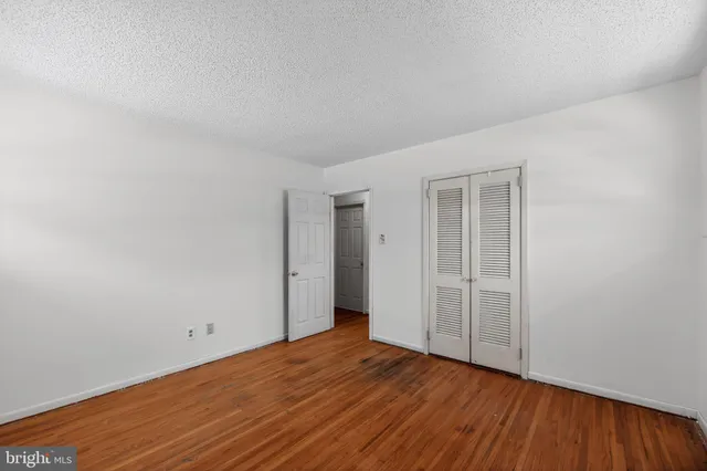 a view of an empty room with wooden floor and closet