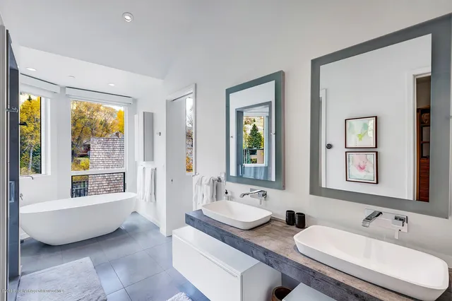 a bathroom with double vanity sinks a tub and a mirror
