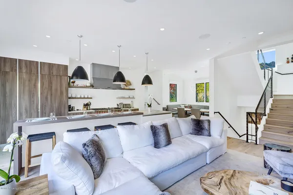 a living room with furniture kitchen area and a wooden floor