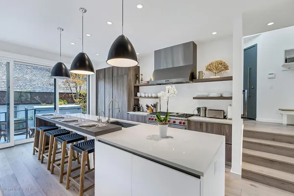a kitchen with stainless steel appliances granite countertop a sink a stove and a wooden floors