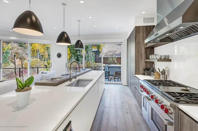 a kitchen with stainless steel appliances granite countertop a sink a stove and a wooden floors