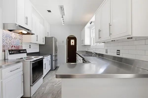 a kitchen with stainless steel appliances a refrigerator sink and cabinets