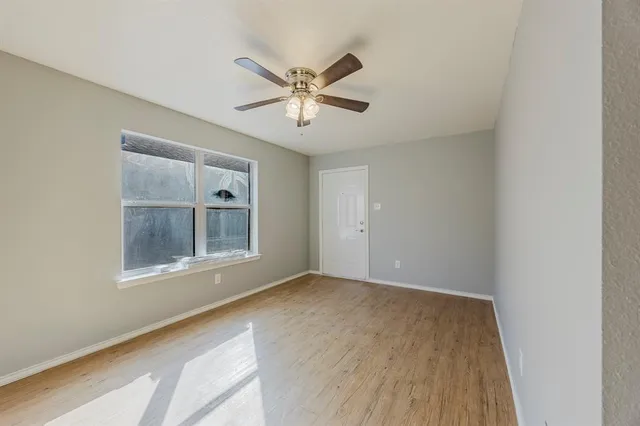 a view of an empty room with a window and wooden floor