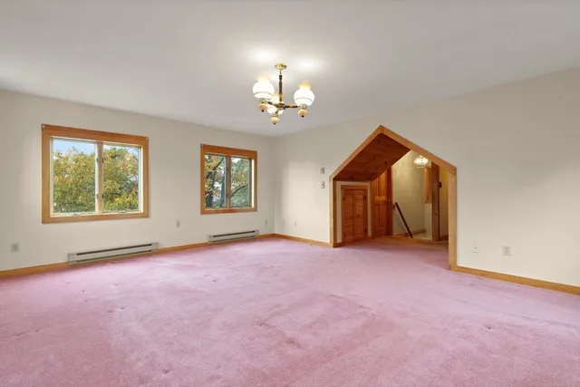 an empty room with windows and chandelier fan