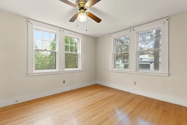a view of an empty room with wooden floor and window