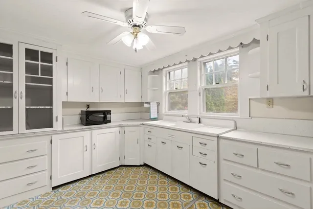 a kitchen with white cabinets and window