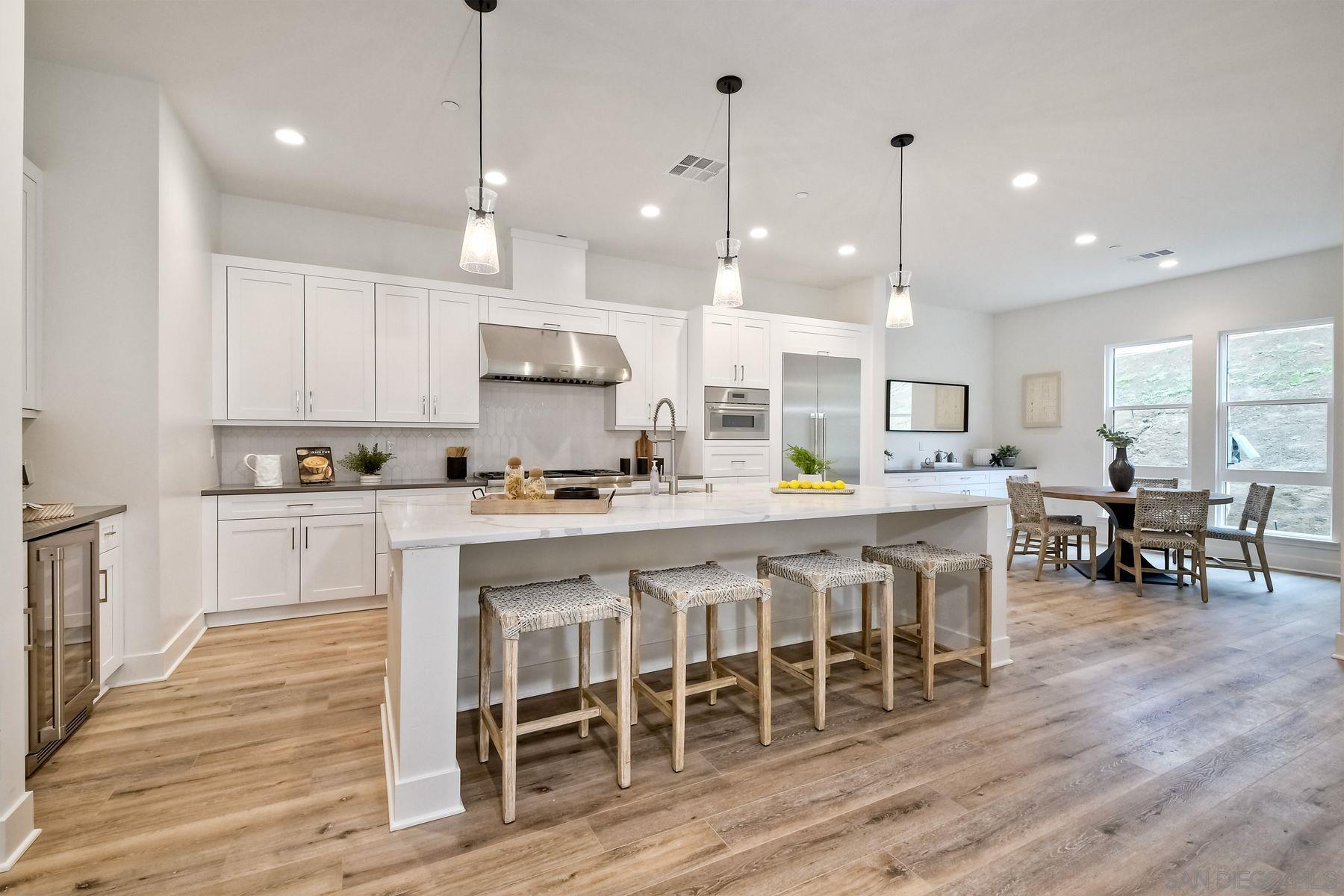 a kitchen with stainless steel appliances kitchen island granite countertop a wooden table chairs and white cabinets