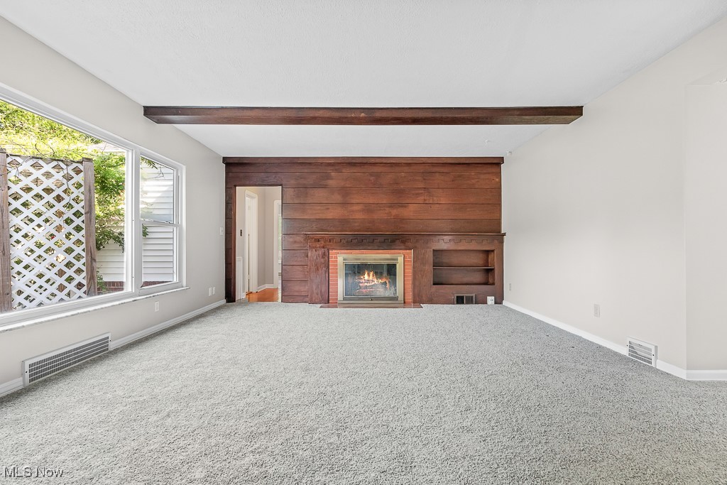 9049 Prospect Road Strongsville, OH 44149 - Photo 4 of 50 Unfurnished living room with beam ceiling, wood walls, and carpet floors