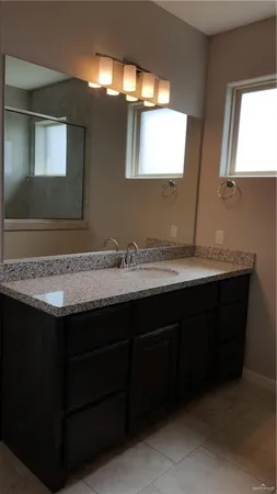 a bathroom with granite countertop a sink and a mirror