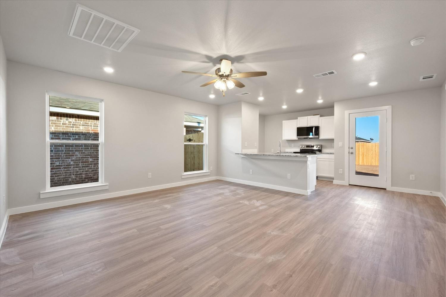 5516 Princeton Street Lubbock, TX 79416 - Photo 3 of 17 a view of a kitchen with a stove cabinets a ceiling fan and wooden floor
