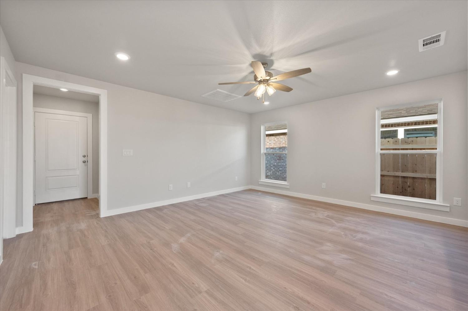 5516 Princeton Street Lubbock, TX 79416 - Photo 6 of 17 an empty room with wooden floor ceiling fan and windows
