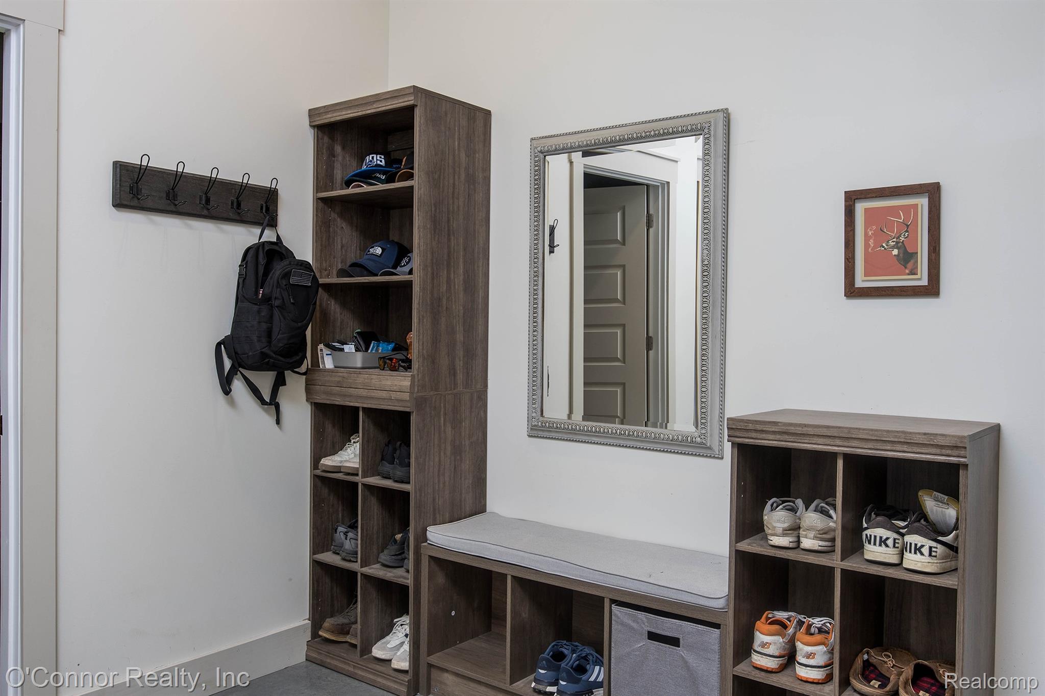 3650 Rabidue Road North Street, MI 48049 - Photo 31 of 53 Entryway featuring a wood-finish storage system with cubbies and open shelving, a coordinating storage bench with a cushion, and a wall-mounted coat rack