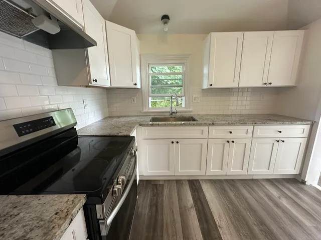 a kitchen with granite countertop white cabinets and black appliances