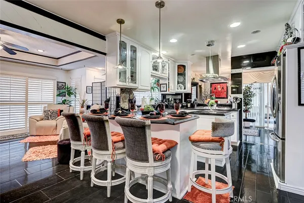 a dining room with stainless steel appliances kitchen island granite countertop a table chairs and a refrigerator