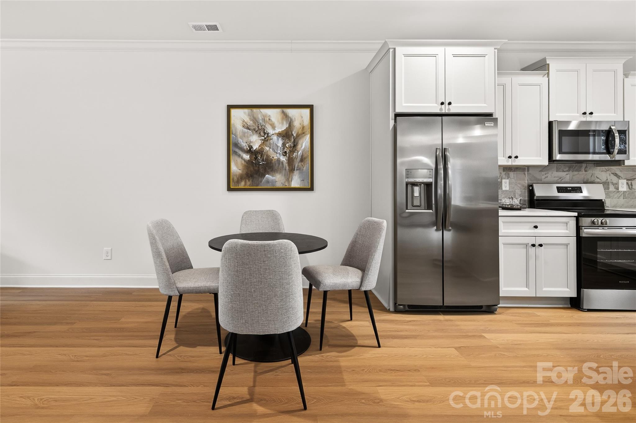13103 Blacksmith Court Matthews, NC 28105 - Photo 8 of 32 a view of a kitchen with stainless steel appliances kitchen island a table chairs in it and white cabinets