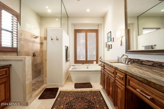 a bathroom with a granite countertop sink mirror and a bathtub