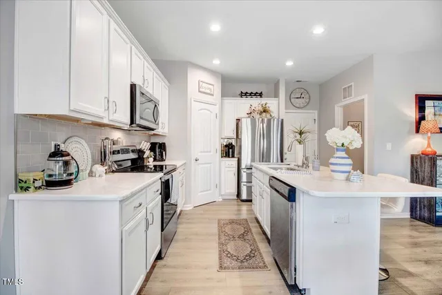 a kitchen with a sink a stove a refrigerator cabinets and a dining table