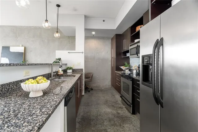 a kitchen with stainless steel appliances granite countertop a refrigerator a oven a sink a dining table and chairs with wooden floor