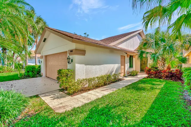 a front view of a house with a yard and potted plants