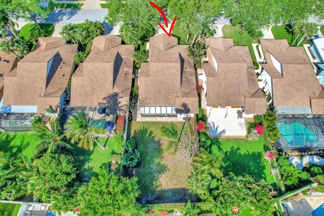 an aerial view of a house with a yard and a large tree