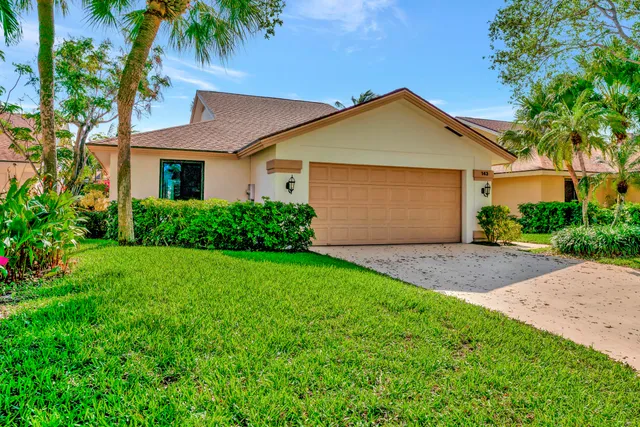 a front view of a house with a garden and tree