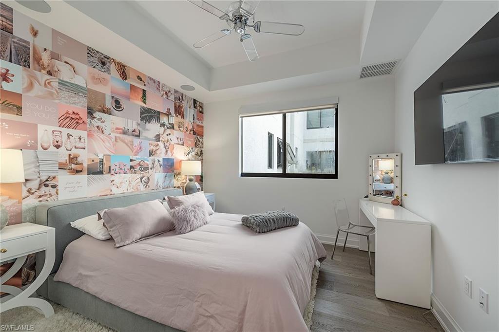 1111 Central Avenue, Unit 310 Naples, FL 34102 - Photo 6 of 12 a bedroom with a bed and a chandelier