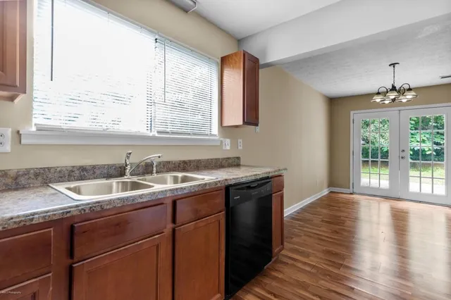 a kitchen with a sink a window and wooden floor