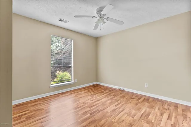 an empty room with windows and ceiling fan