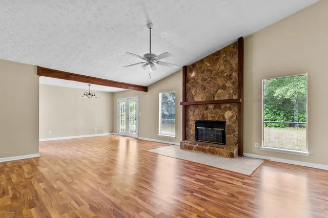 an empty room with windows fireplace and wooden floor
