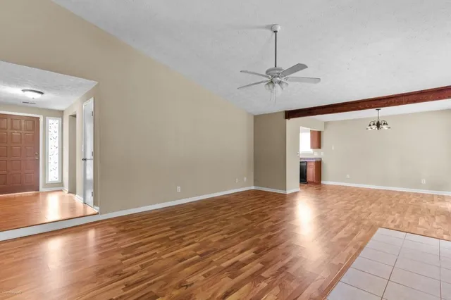 a view of an empty room with window and wooden floor
