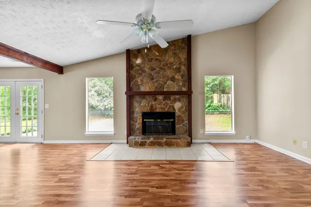 an empty room with windows and fireplace