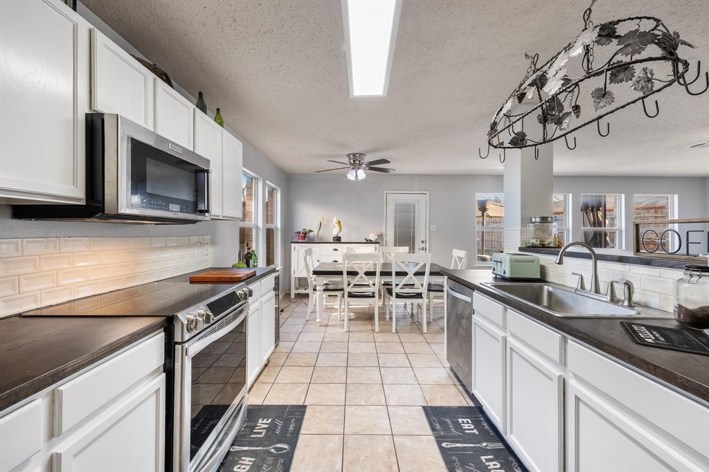 1609 Jester Court Little Elm, TX 75036 - Photo 16 of 34 a kitchen with stainless steel appliances a sink a stove top oven a chimney cabinets and a dining table