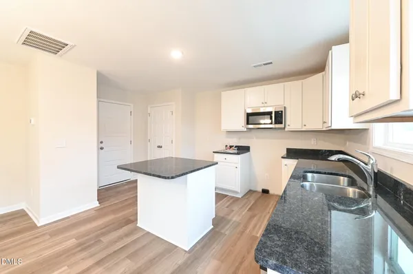 a kitchen with stainless steel appliances granite countertop a sink and a stove top oven with wooden floor
